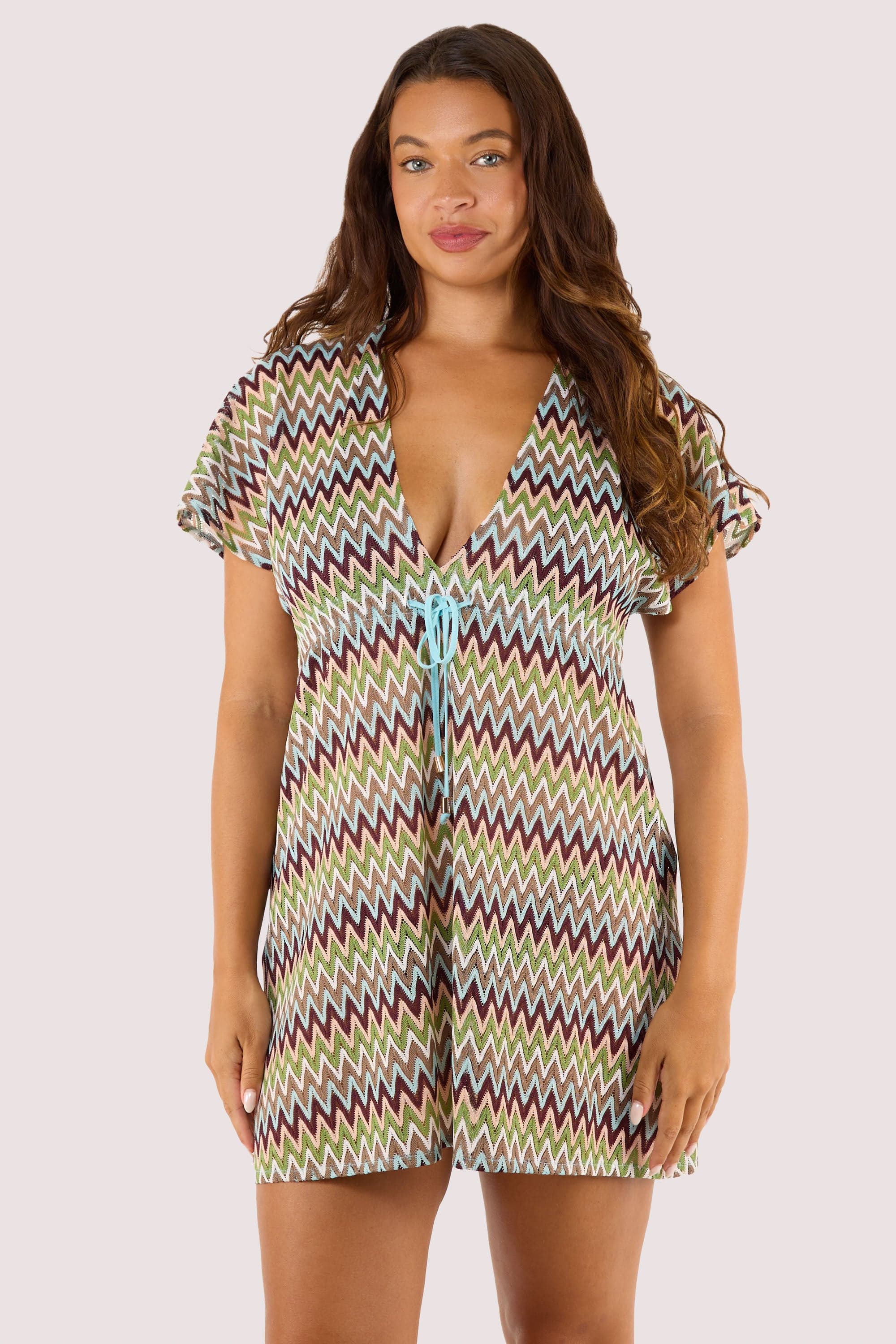 Model displays a bright chevron print swimsuit under a flowing, lightweight crochet kaftan with a zig-zag design.