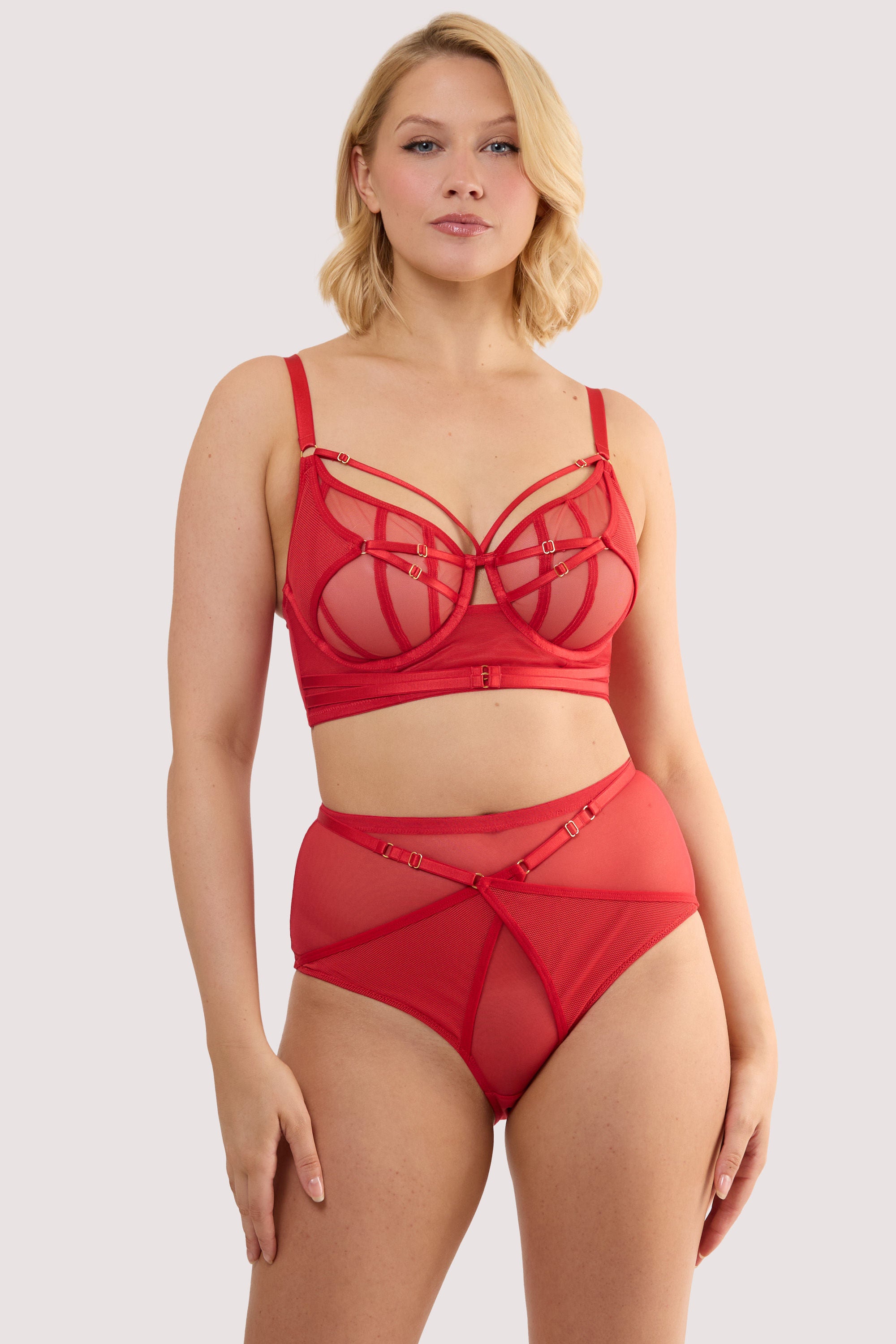 Model wears a eddie ruby red crossover balconette bra with longline style and sheer mesh and fishnet panels, with a matching high waist thong.