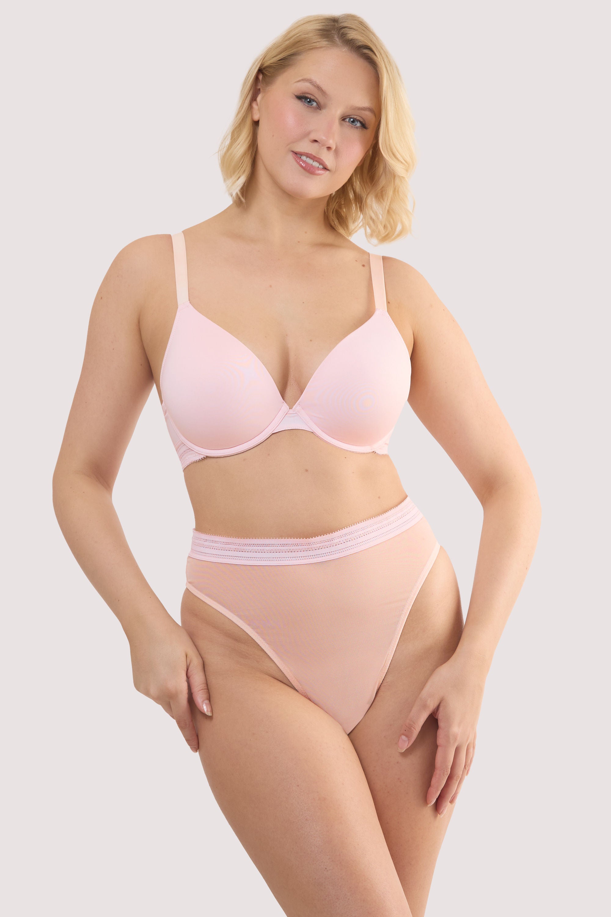 Model wears a icon blush pink sheer plunge bra with light pink mesh longline style and underwired, full cups with a matching high waist brief.