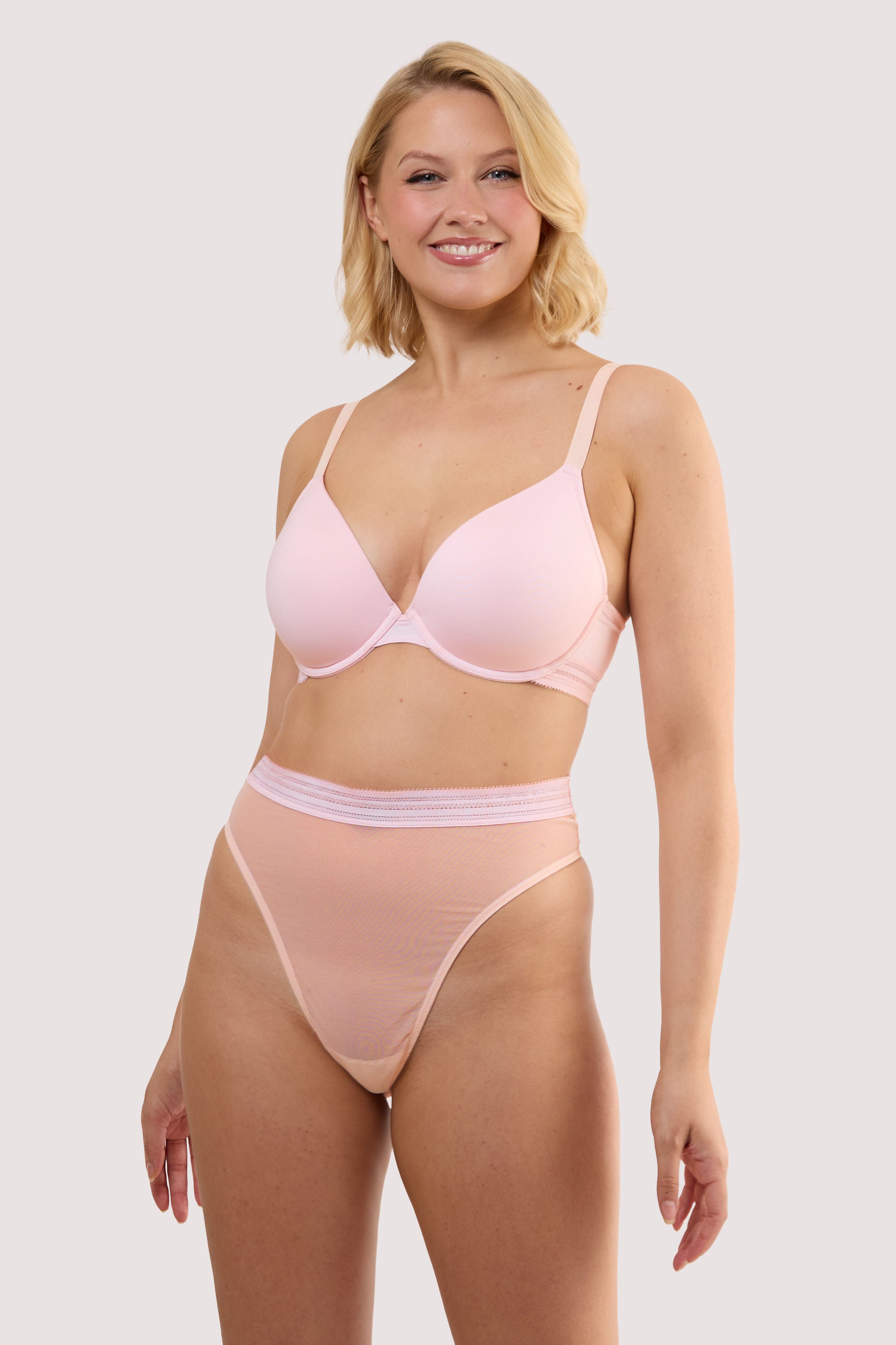 Model wears a icon blush pink high waist thong with light pink supportive mesh and Linear waistband trim with a matching bra.