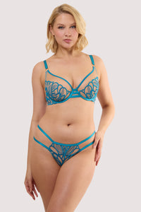 Model wears a lilith teal graphic embroidery thong with sheer mesh with teal embroidery featuring satin elastic side bands with a matching bra.