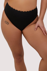 model wears black scalloped high waist bikini bottoms