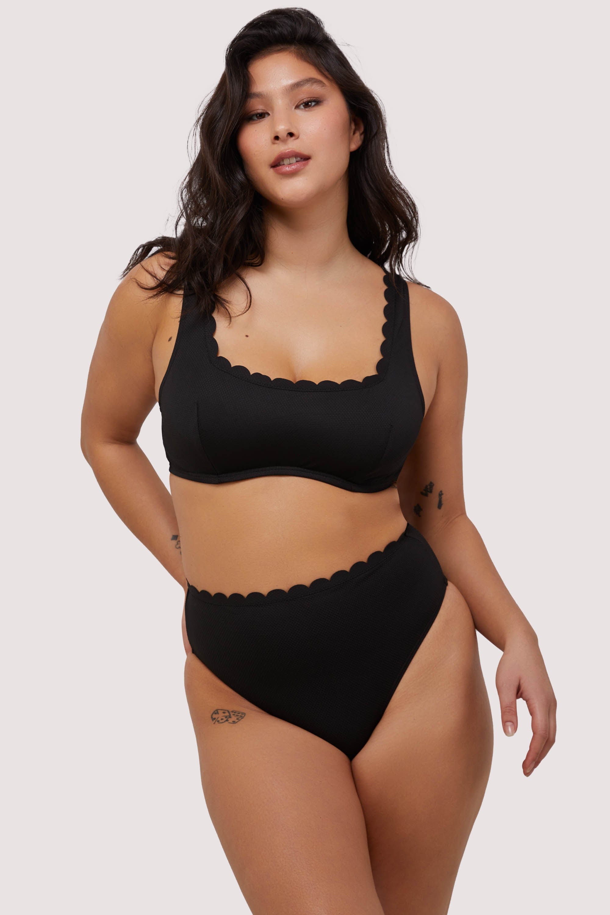 model wears black scalloped underwire balconette bikini top with matching high leg bottoms swimwear set