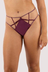 Model wears a wine high waist brief featuring a satin central panel, strap detailing, and gold metal hardware.