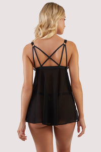 Back view of a black babydoll dress with art deco style cups, cage detailing on the bust and a clasp between the cups, with criss-cross straps at the back.
